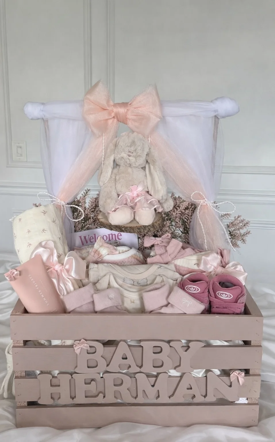 Pink baby shower basket with large bow, personalized crate, and soft keepsake details