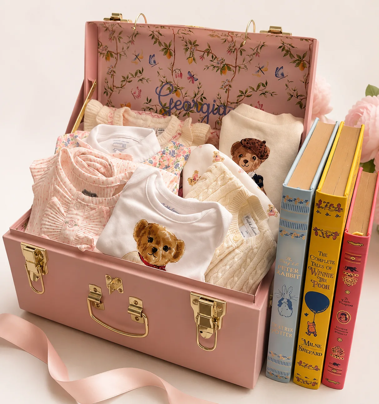 Pink heirloom baby gift trunk with keepsake clothing, classic books, and personalized details